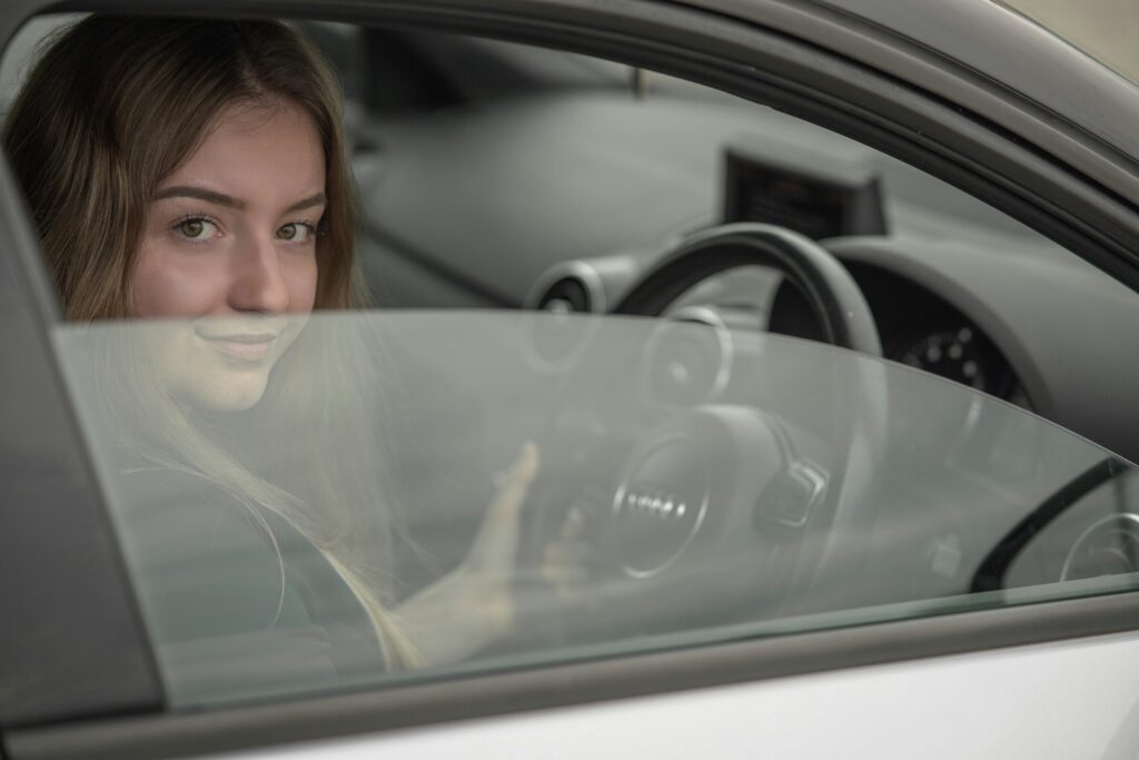 A young woman sitting in a car and holding the steering wheel
