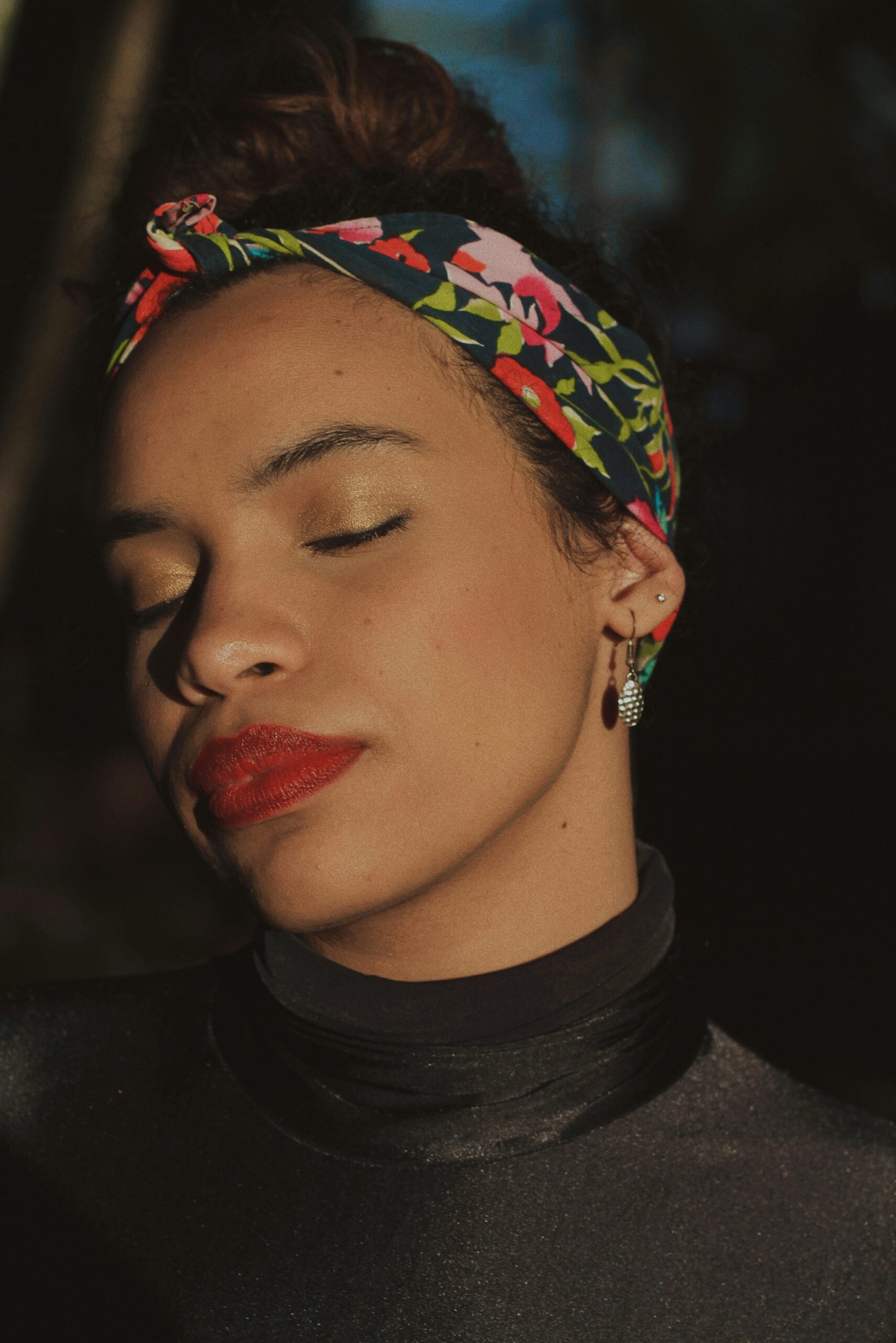 A closeup of a woman wearing a patterned scarf with a messy bun