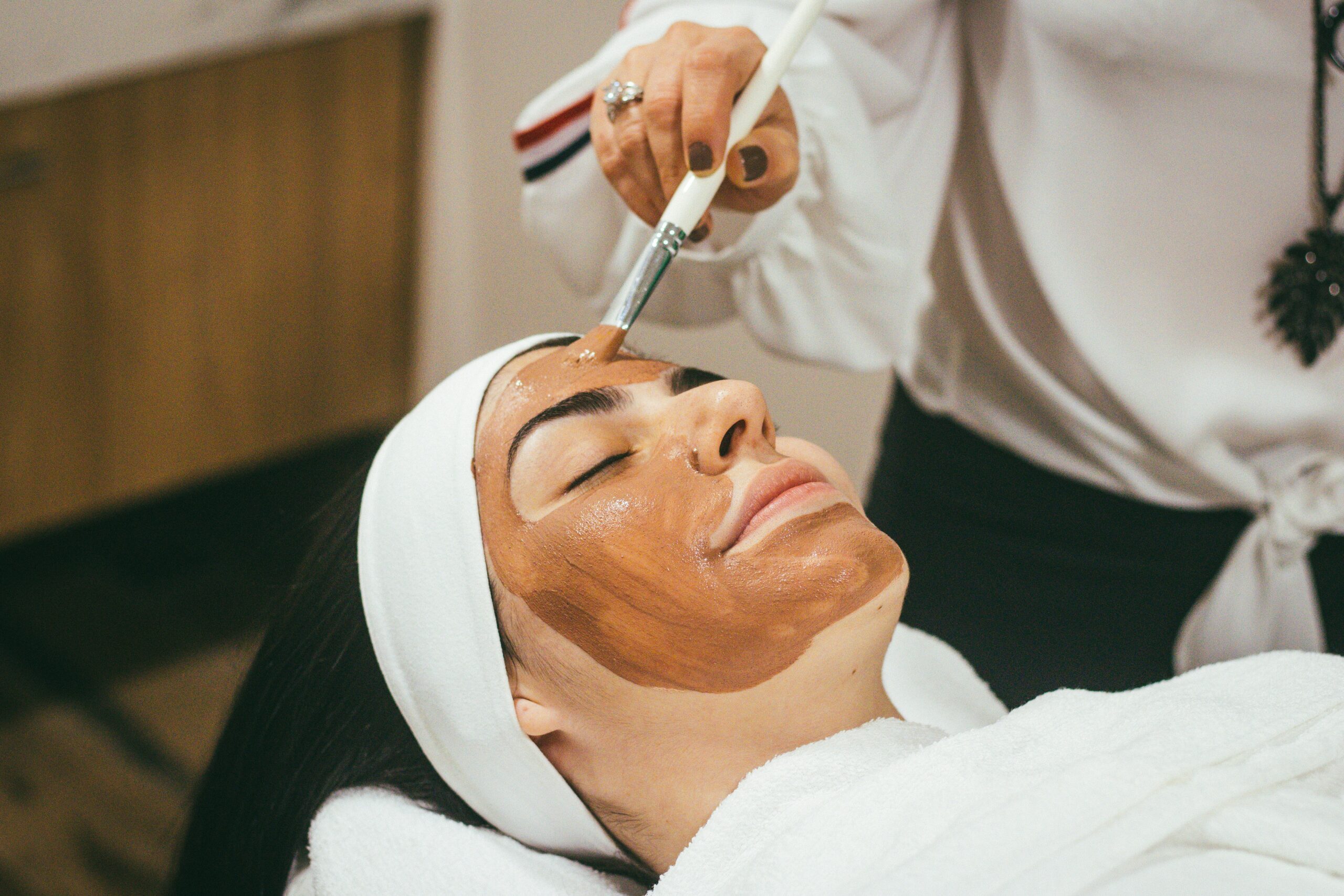 A closeup of a woman receiving a mud mask as part of a facial