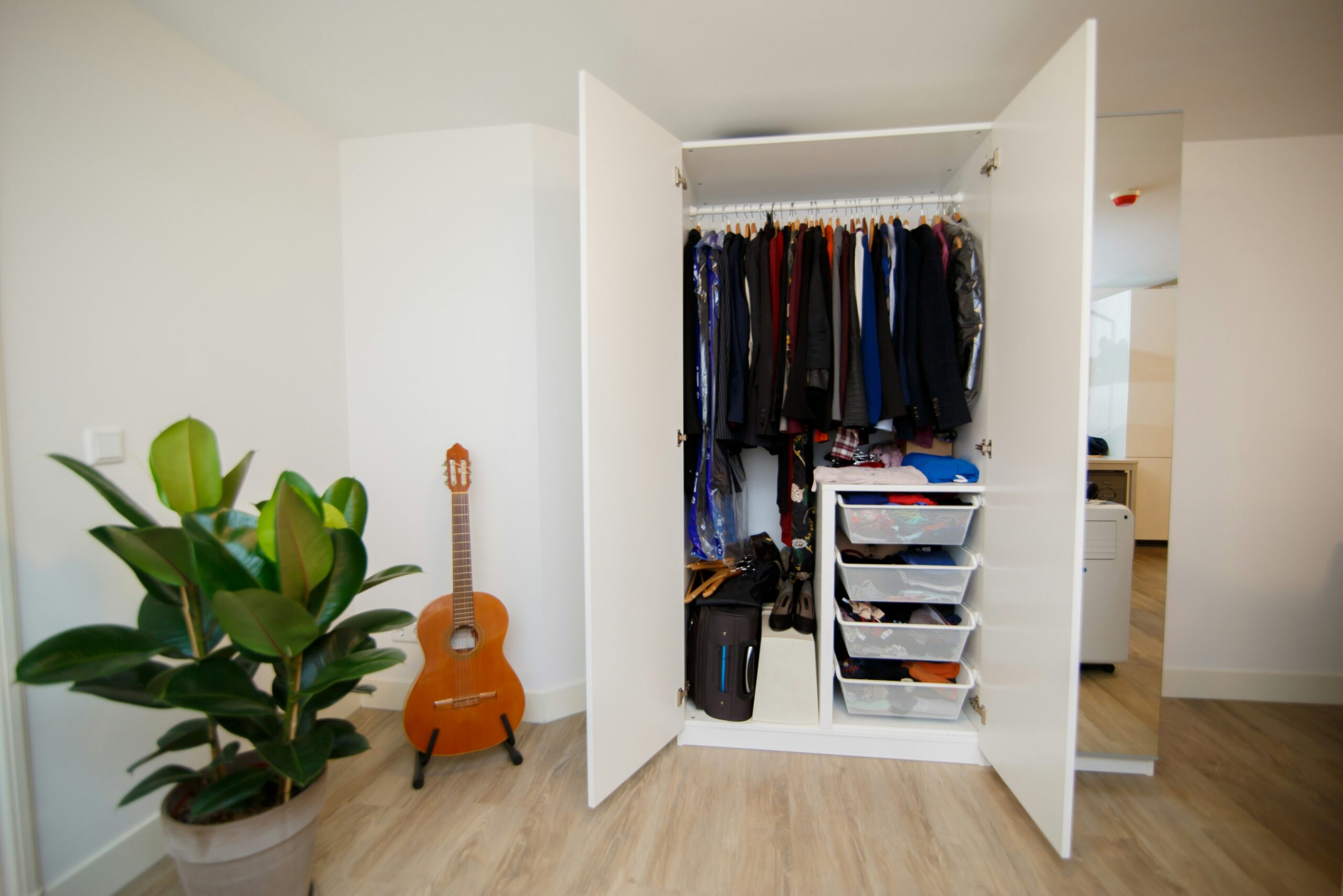 A small closet with clothes on hangers and in drawers