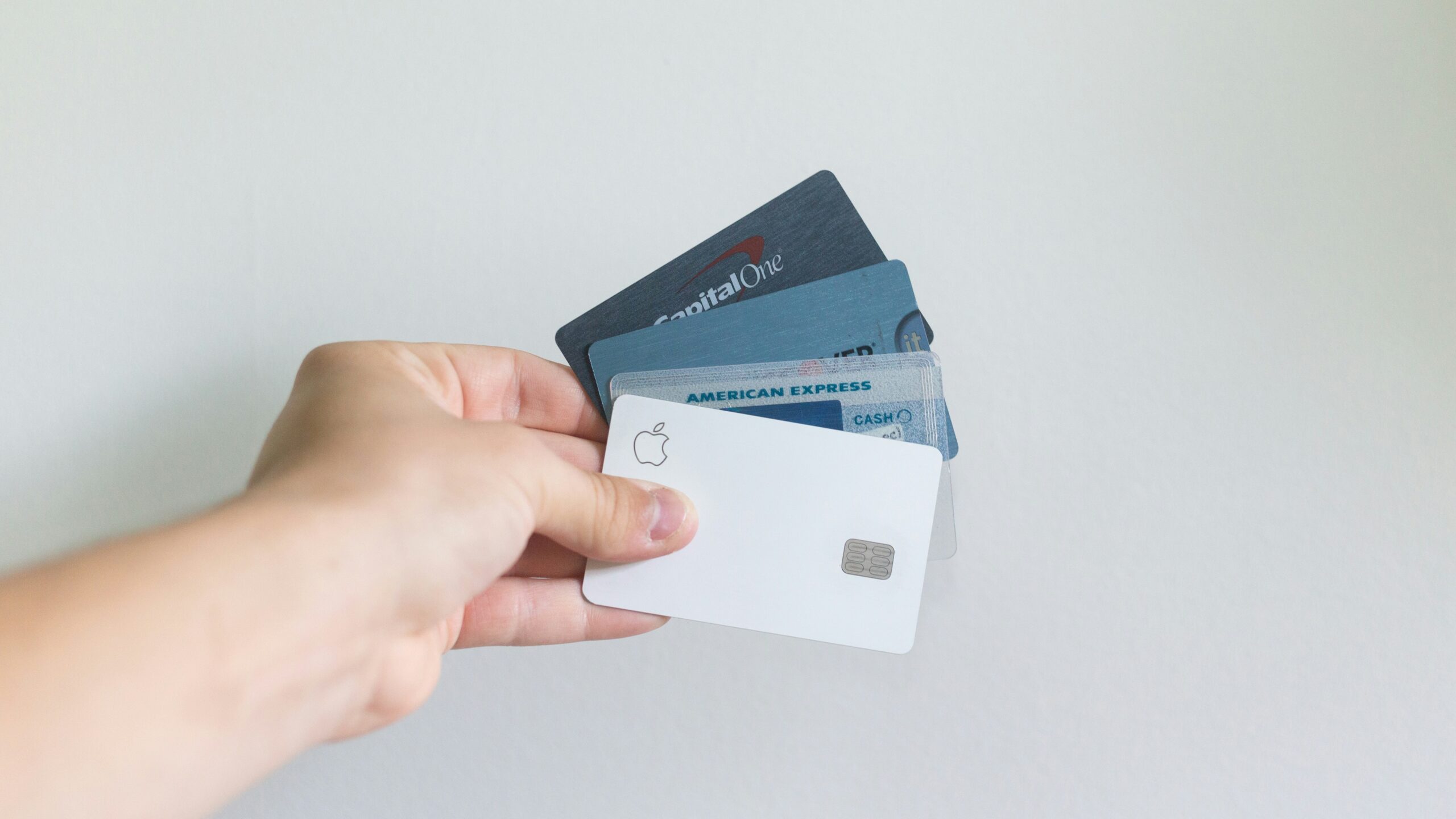 A hand holding 4 different credit cards