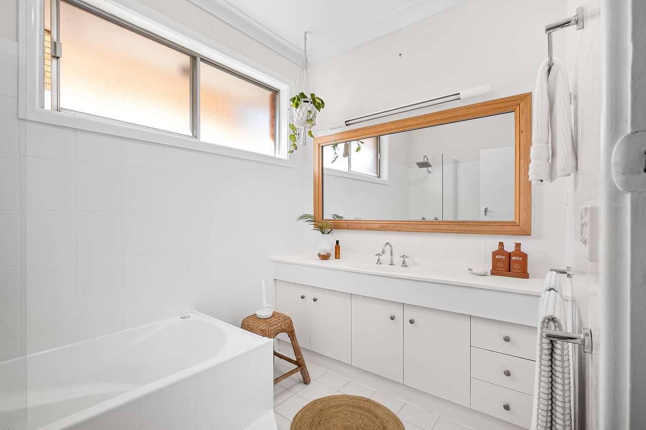 A white bathroom with a bathtub and sink and wooden, wicker accents