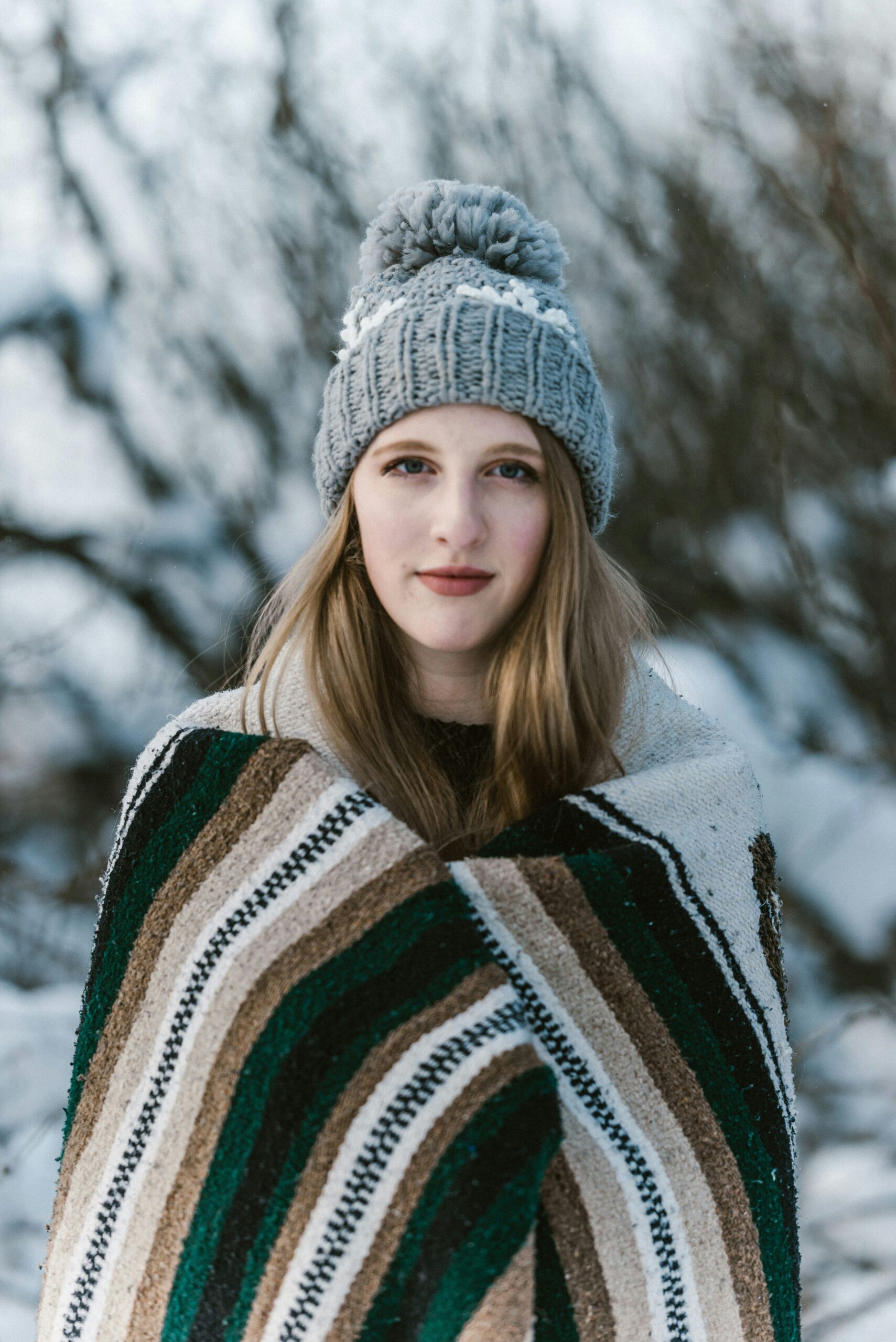 A woman with medium length blonde hair wearing a grey winter hat in the snow