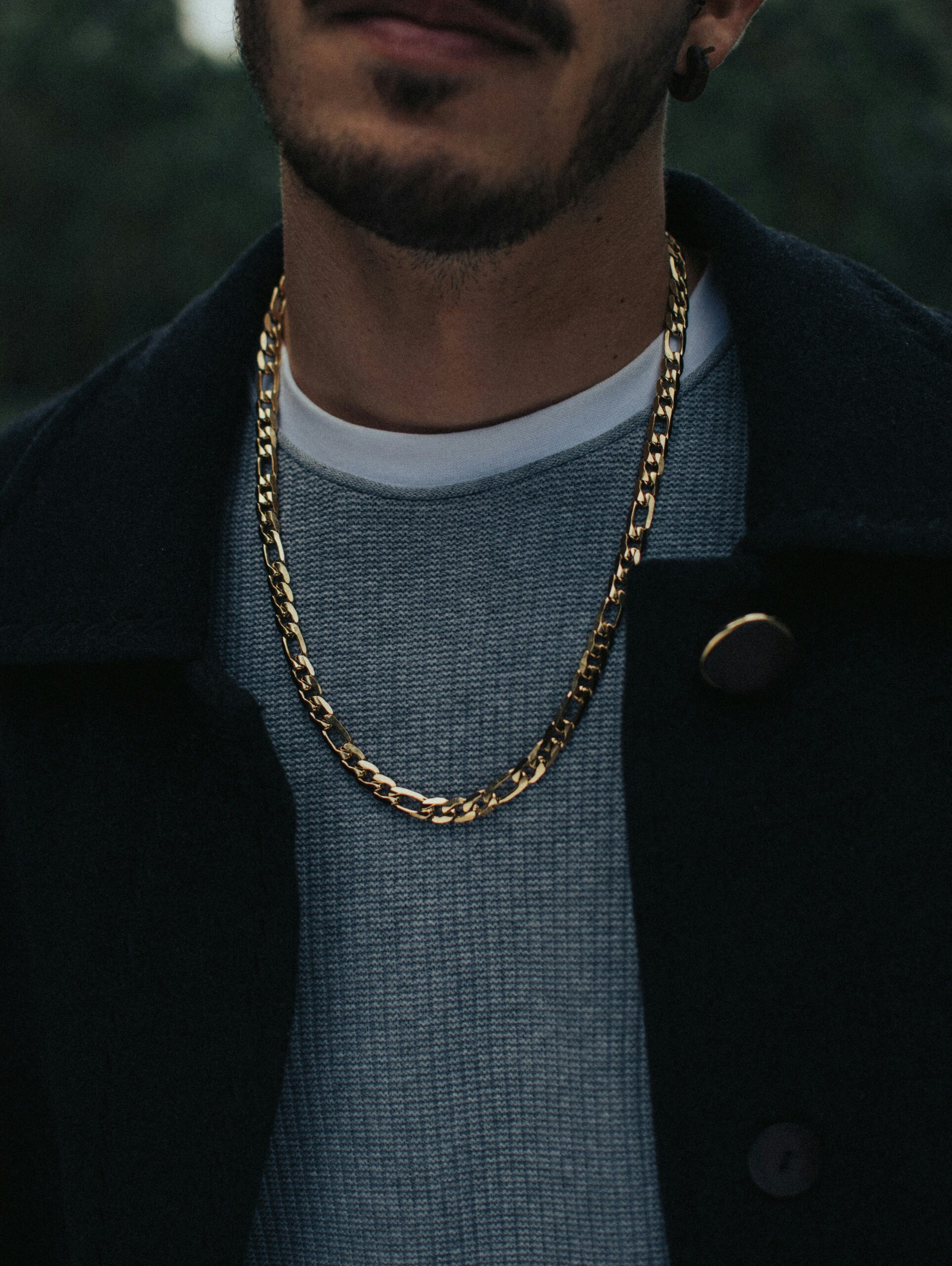 A close up of a mean wearing a jacket with a gold chain