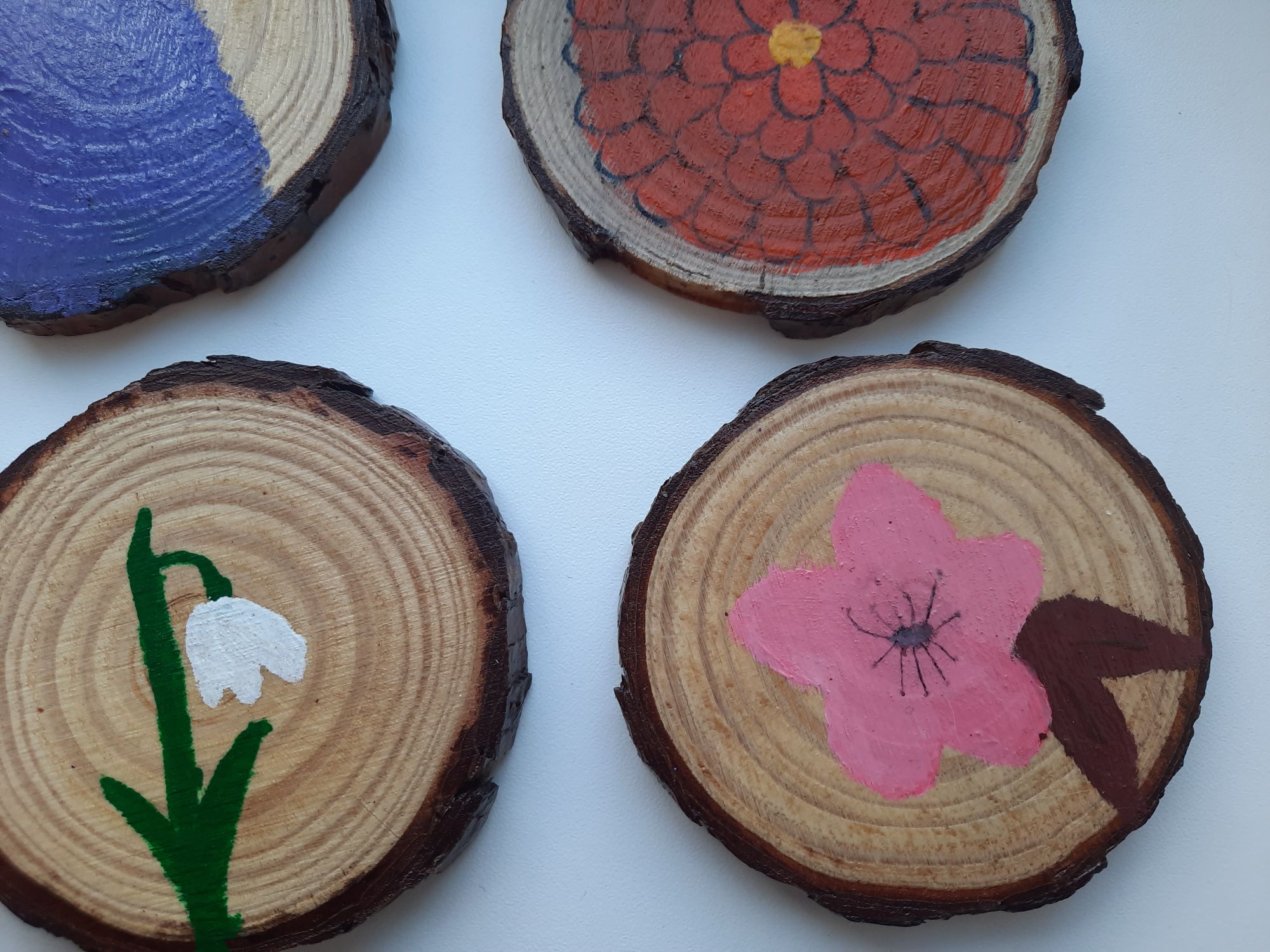 Small wood slices panted with a cherry blossom, snowdrop, chrysanthemum, and lavender