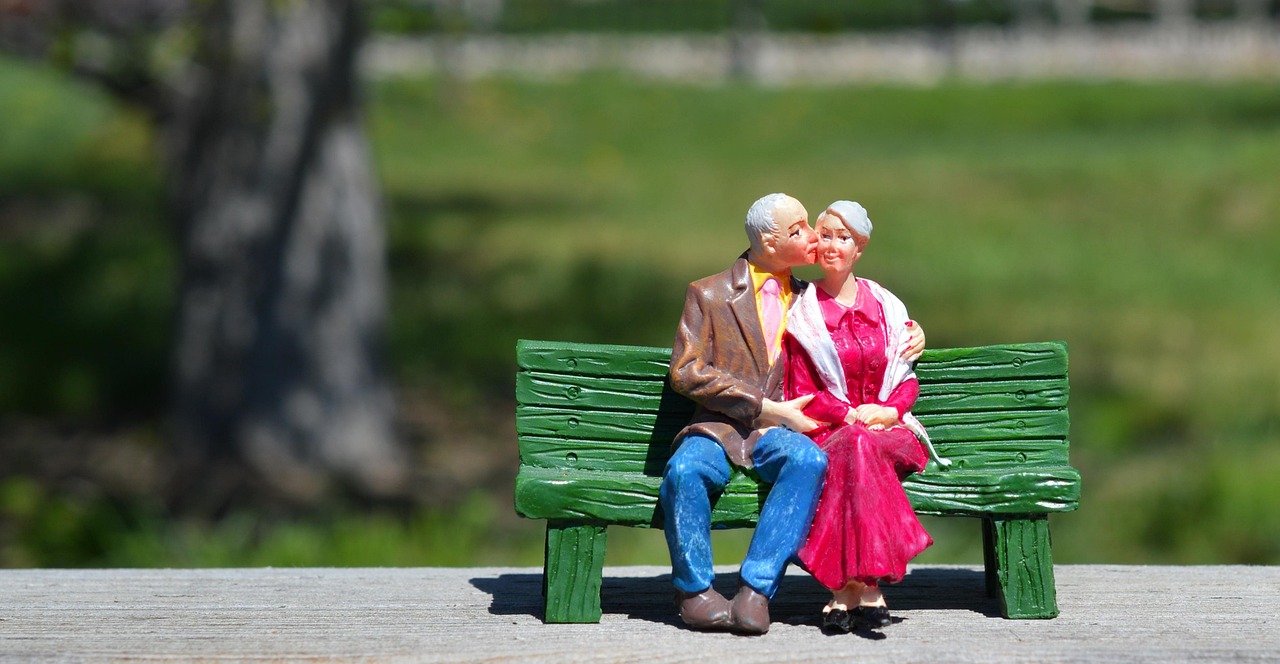 A figurine of a retired couple sitting on a green bench