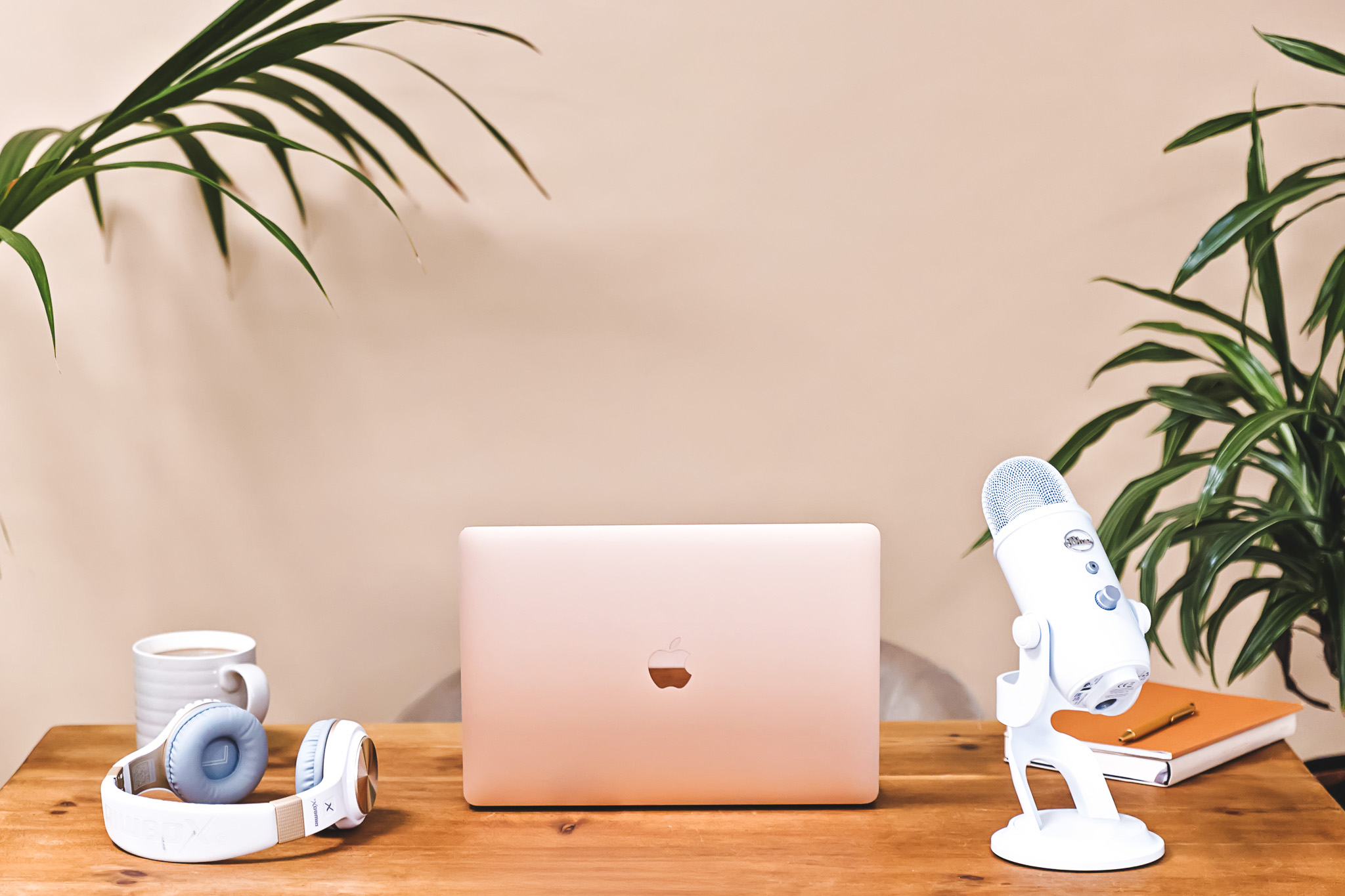A laptop on a wooden desk next to a pair of headphones and a microphone.