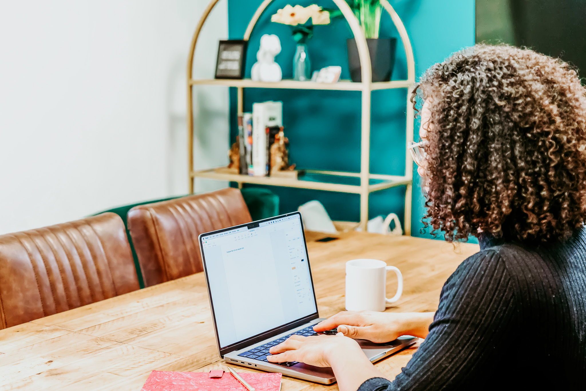A woman sitting at a laptop with a journal next to her.