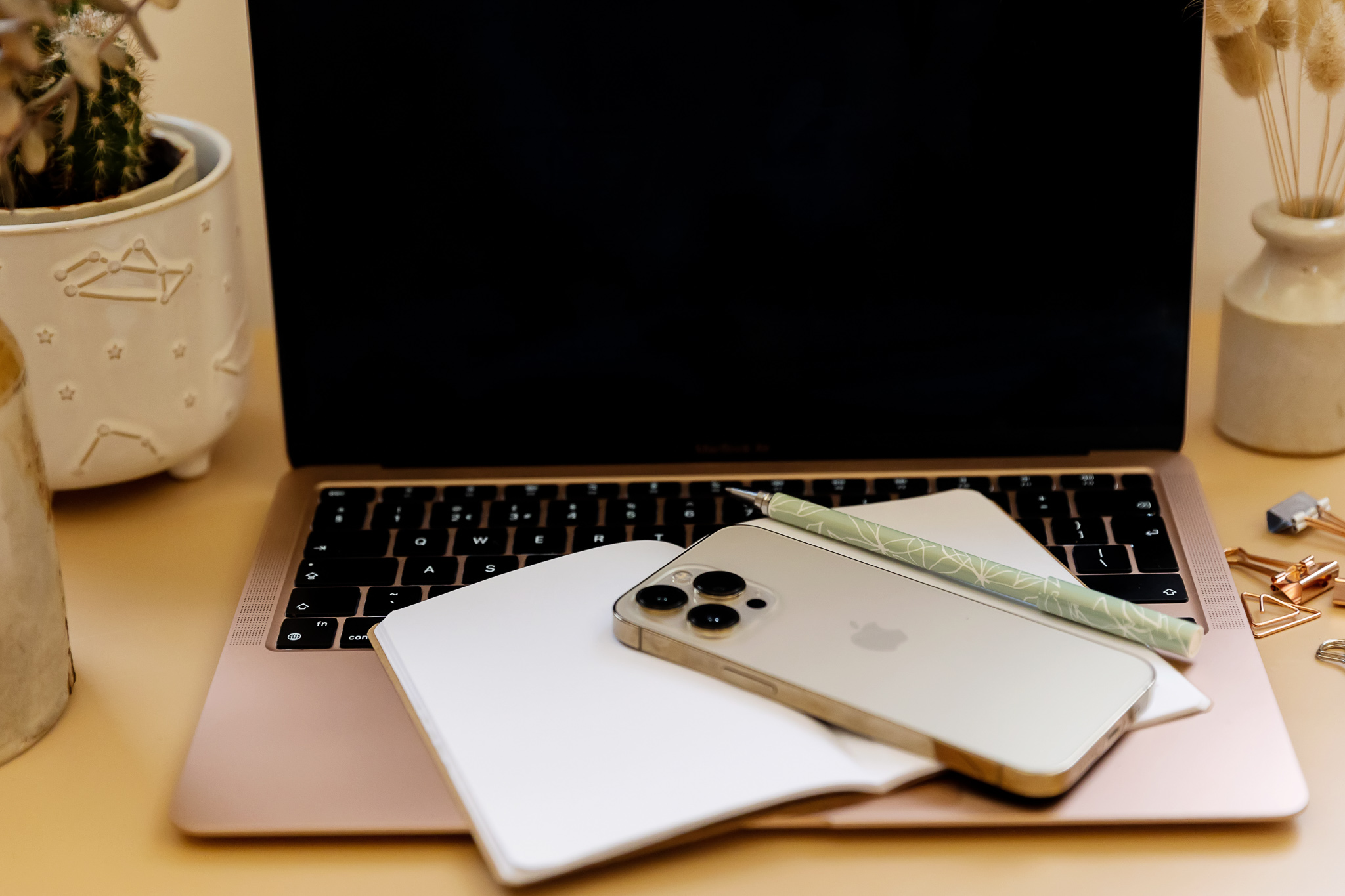 An iPhone laid on top of an open notebook and an opened laptop