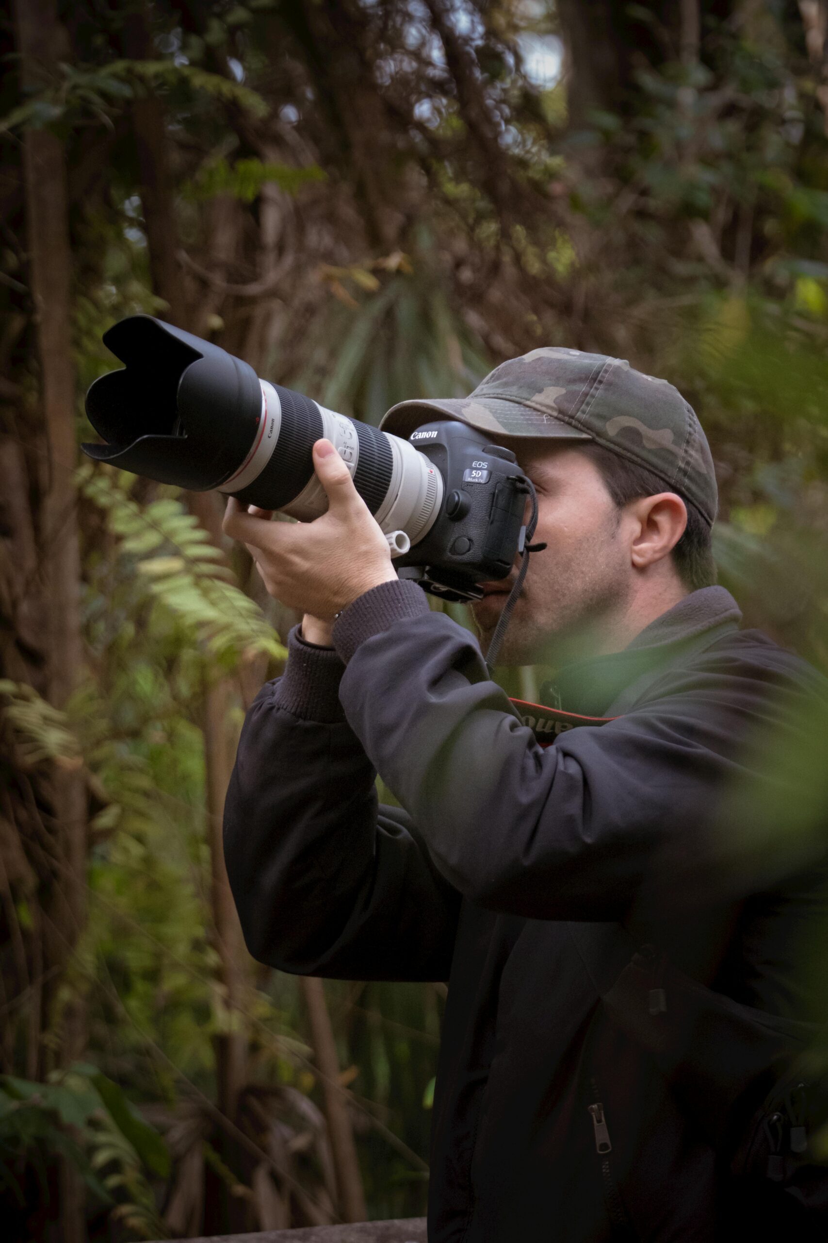 A photographer in nature using a large camera lens.
