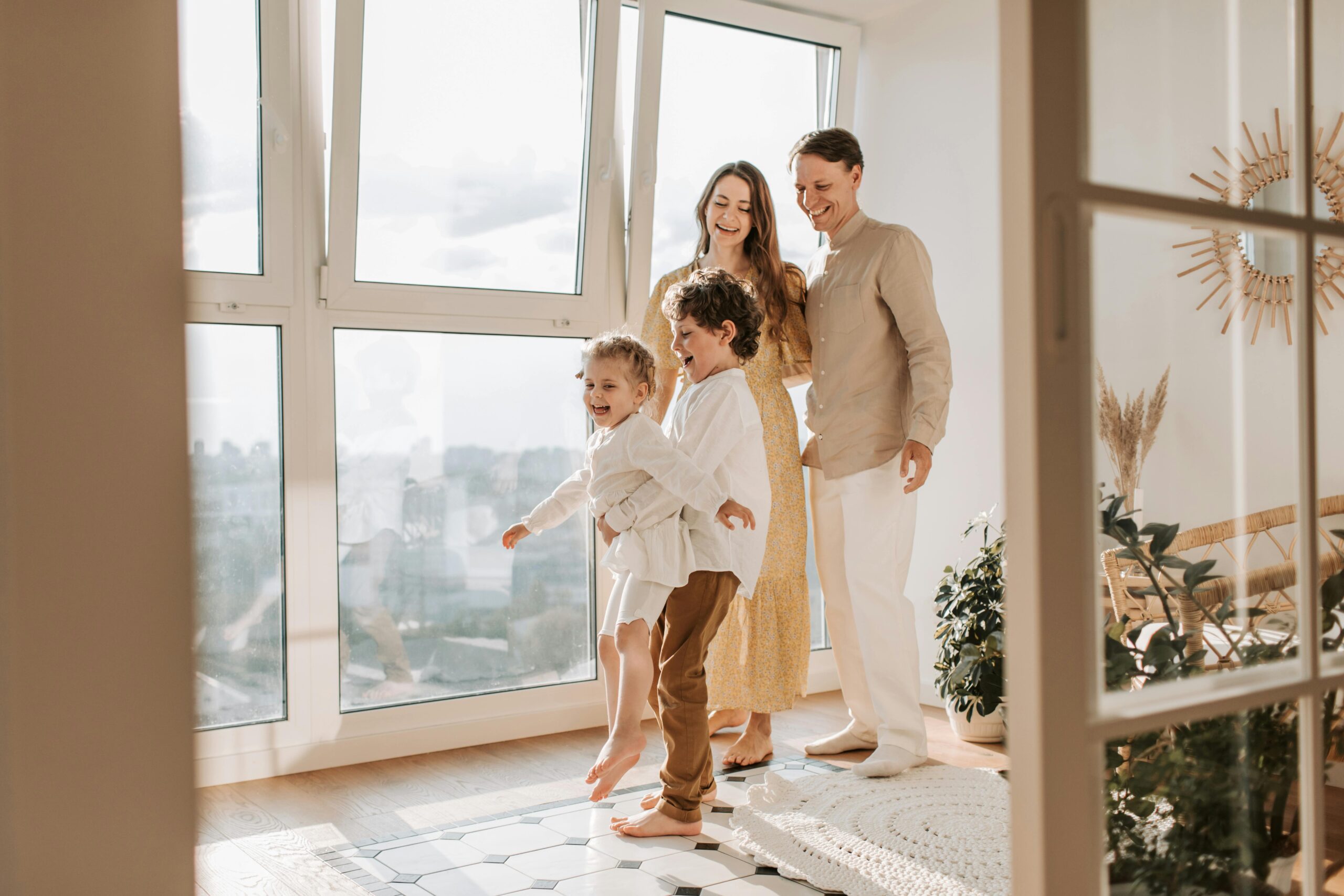A family of four standing and smiling in a living room