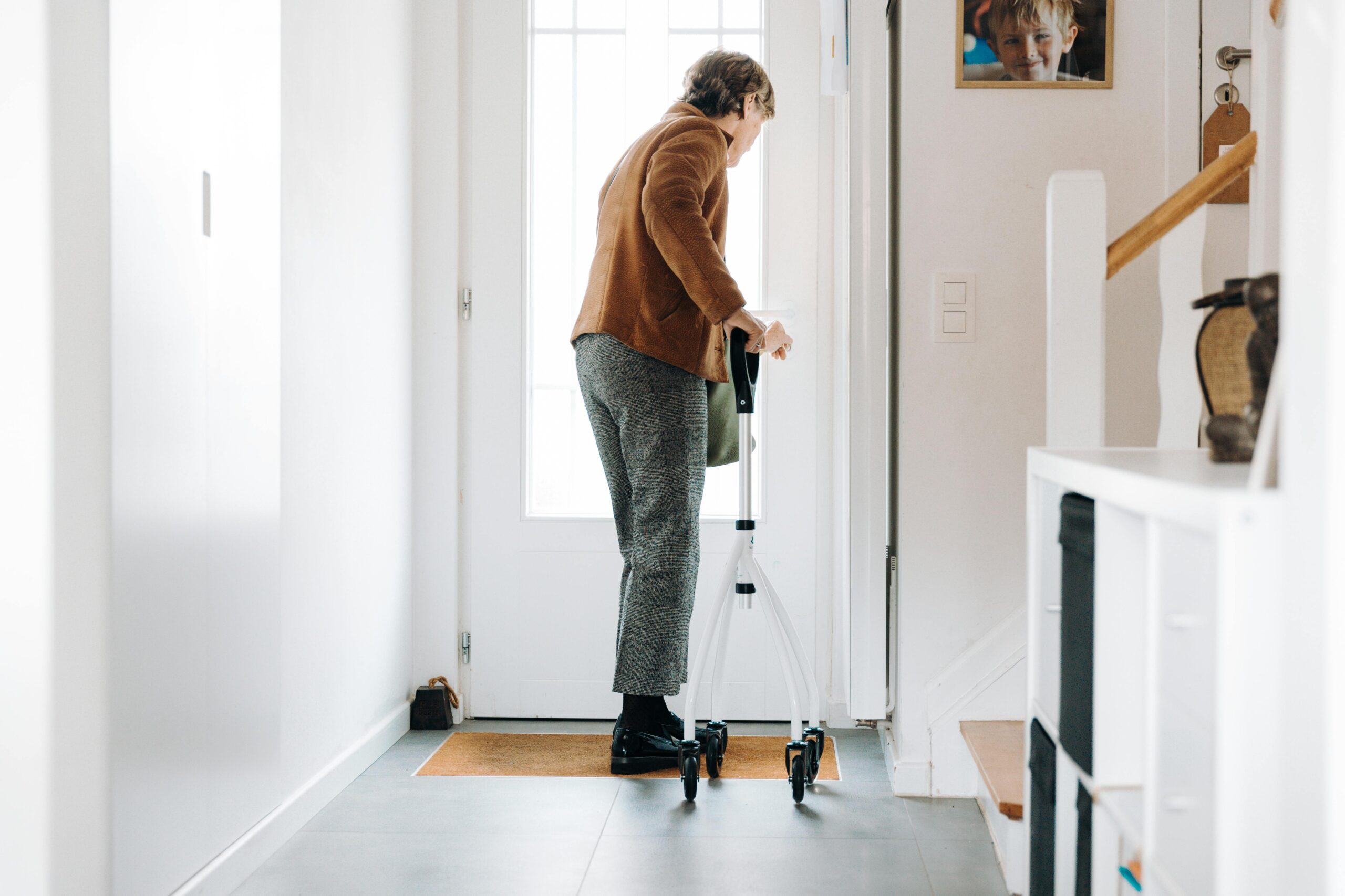 An older adult using a rollator walker in an entryway that is clear of clutter and other obstacles