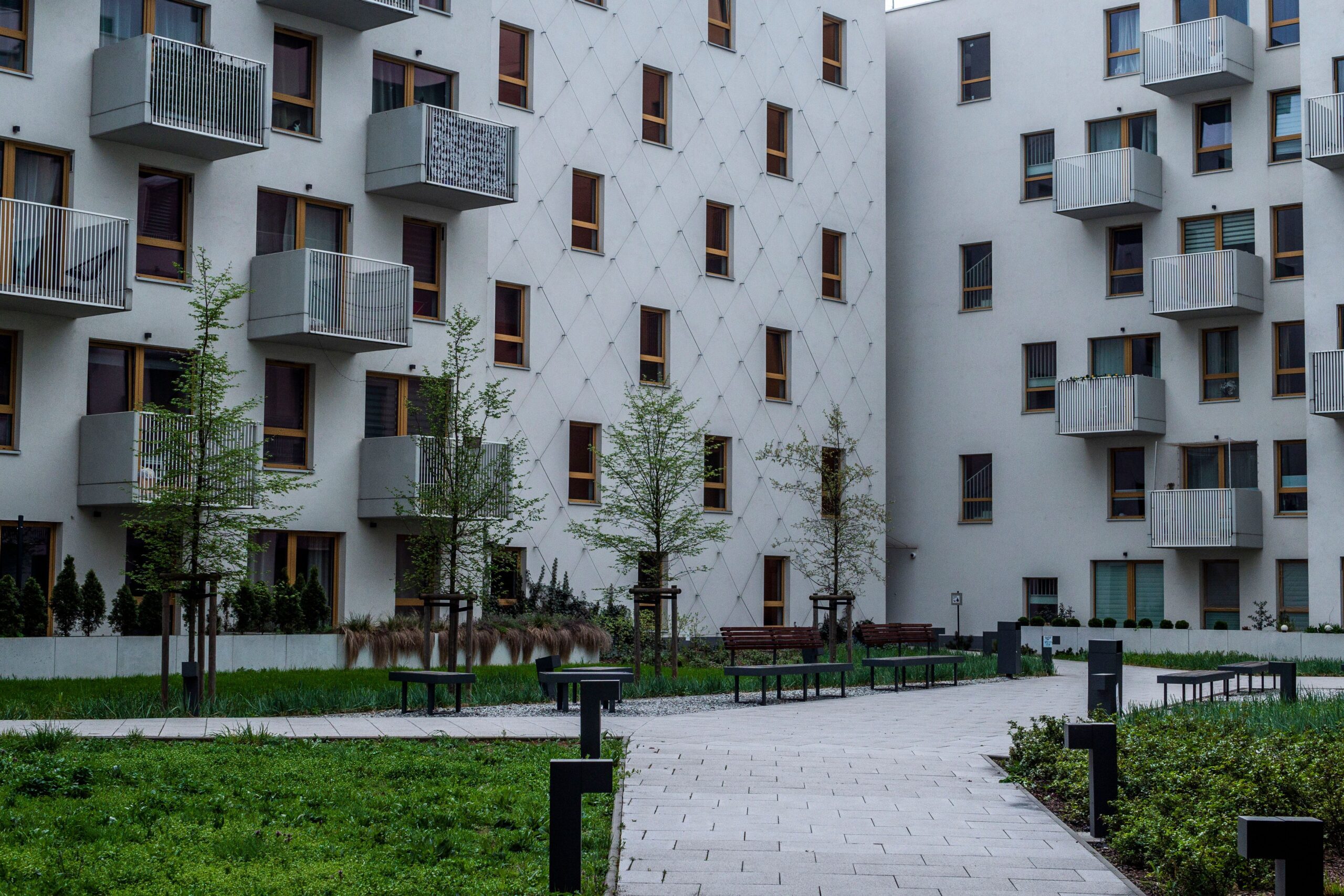 An exterior of an apartment complex with a well-maintained walkway with lights along the path